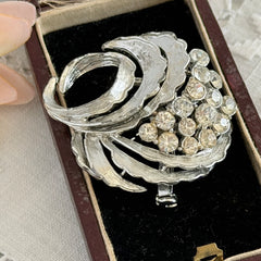 Vintage silver tone swirl leaf brooch with clear rhinestone cluster, textured metal, 1970s–1980s.