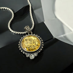 Vintage Cookie Lee necklace featuring a faceted yellow Lucite pendant with a rose intaglio in an ornate silver tone setting, hanging from a thick serpentine chain.