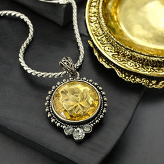 Vintage Cookie Lee necklace featuring a faceted yellow Lucite pendant with a rose intaglio in an ornate silver tone setting, hanging from a thick serpentine chain.