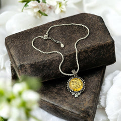 Vintage Cookie Lee necklace featuring a faceted yellow Lucite pendant with a rose intaglio in an ornate silver tone setting, hanging from a thick serpentine chain.