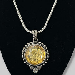 Vintage Cookie Lee necklace featuring a faceted yellow Lucite pendant with a rose intaglio in an ornate silver tone setting, hanging from a thick serpentine chain.
