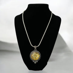 Vintage Cookie Lee necklace featuring a faceted yellow Lucite pendant with a rose intaglio in an ornate silver tone setting, hanging from a thick serpentine chain.