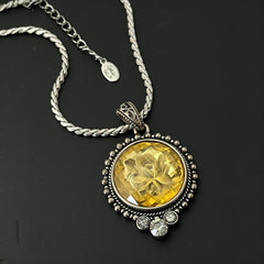Vintage Cookie Lee necklace featuring a faceted yellow Lucite pendant with a rose intaglio in an ornate silver tone setting, hanging from a thick serpentine chain.