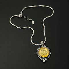 Vintage Cookie Lee necklace featuring a faceted yellow Lucite pendant with a rose intaglio in an ornate silver tone setting, hanging from a thick serpentine chain.