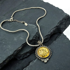 Vintage Cookie Lee necklace featuring a faceted yellow Lucite pendant with a rose intaglio in an ornate silver tone setting, hanging from a thick serpentine chain.