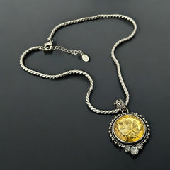 Vintage Cookie Lee necklace featuring a faceted yellow Lucite pendant with a rose intaglio in an ornate silver tone setting, hanging from a thick serpentine chain.