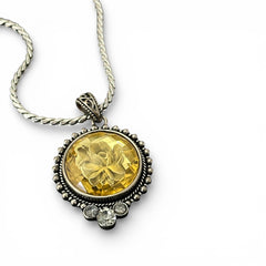 Vintage Cookie Lee necklace featuring a faceted yellow Lucite pendant with a rose intaglio in an ornate silver tone setting, hanging from a thick serpentine chain.