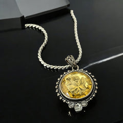 Vintage Cookie Lee necklace featuring a faceted yellow Lucite pendant with a rose intaglio in an ornate silver tone setting, hanging from a thick serpentine chain.