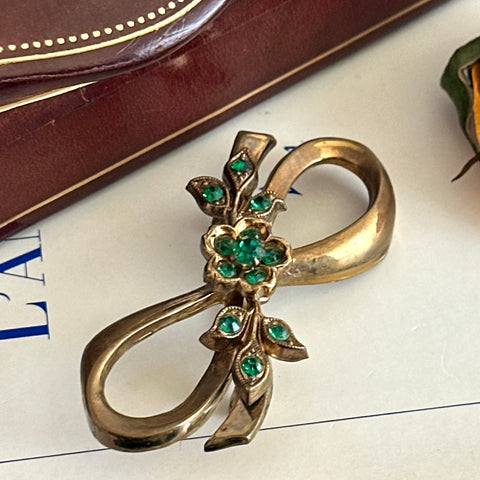 Vintage Coro Pegasus gold‑tone bow brooch with an emerald rhinestone floral center, shown from various angles to highlight its sculptural mid‑century design.