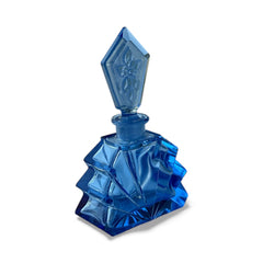 Vintage Czech Art Deco sapphire blue fan‑shaped perfume bottle with geometric stopper and frosted intaglio floral dauber, shown in styled settings that highlight its faceted design, vibrant color, and collectible craftsmanship.