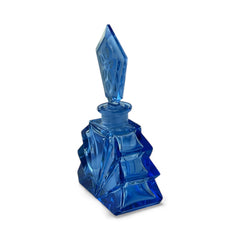 Vintage Czech Art Deco sapphire blue fan‑shaped perfume bottle with geometric stopper and frosted intaglio floral dauber, shown in styled settings that highlight its faceted design, vibrant color, and collectible craftsmanship.