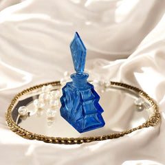 Vintage Czech Art Deco sapphire blue fan‑shaped perfume bottle with geometric stopper and frosted intaglio floral dauber, shown in styled settings that highlight its faceted design, vibrant color, and collectible craftsmanship.
