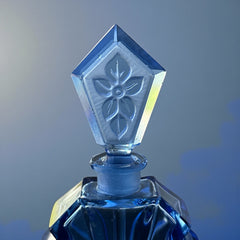 Vintage Czech Art Deco sapphire blue fan‑shaped perfume bottle with geometric stopper and frosted intaglio floral dauber, shown in styled settings that highlight its faceted design, vibrant color, and collectible craftsmanship.