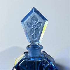 Vintage Czech Art Deco sapphire blue fan‑shaped perfume bottle with geometric stopper and frosted intaglio floral dauber, shown in styled settings that highlight its faceted design, vibrant color, and collectible craftsmanship.