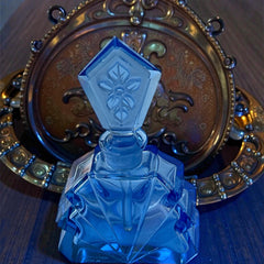 Vintage Czech Art Deco sapphire blue fan‑shaped perfume bottle with geometric stopper and frosted intaglio floral dauber, shown in styled settings that highlight its faceted design, vibrant color, and collectible craftsmanship.