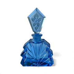 Vintage Czech Art Deco sapphire blue fan‑shaped perfume bottle with geometric stopper and frosted intaglio floral dauber, shown in styled settings that highlight its faceted design, vibrant color, and collectible craftsmanship.