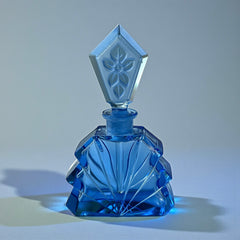 Vintage Czech Art Deco sapphire blue fan‑shaped perfume bottle with geometric stopper and frosted intaglio floral dauber, shown in styled settings that highlight its faceted design, vibrant color, and collectible craftsmanship.