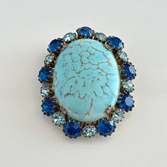Vintage Czech statement brooch featuring a large faux turquoise Hubbell glass oval cabochon surrounded by alternating capri blue and light sapphire rhinestones in a gold‑tone prong‑set setting, shown from various angles.