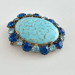 Vintage Czech statement brooch featuring a large faux turquoise Hubbell glass oval cabochon surrounded by alternating capri blue and light sapphire rhinestones in a gold‑tone prong‑set setting, shown from various angles.