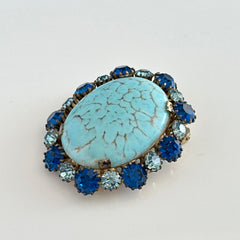 Vintage Czech statement brooch featuring a large faux turquoise Hubbell glass oval cabochon surrounded by alternating capri blue and light sapphire rhinestones in a gold‑tone prong‑set setting, shown from various angles.