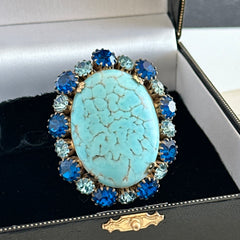Vintage Czech statement brooch featuring a large faux turquoise Hubbell glass oval cabochon surrounded by alternating capri blue and light sapphire rhinestones in a gold‑tone prong‑set setting, shown from various angles.