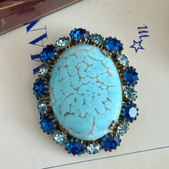 Vintage Czech statement brooch featuring a large faux turquoise Hubbell glass oval cabochon surrounded by alternating capri blue and light sapphire rhinestones in a gold‑tone prong‑set setting, shown from various angles.