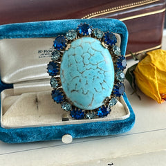 Vintage Czech statement brooch featuring a large faux turquoise Hubbell glass oval cabochon surrounded by alternating capri blue and light sapphire rhinestones in a gold‑tone prong‑set setting, shown from various angles.