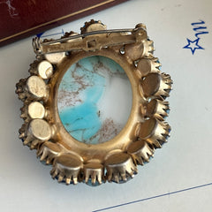 Vintage Czech statement brooch featuring a large faux turquoise Hubbell glass oval cabochon surrounded by alternating capri blue and light sapphire rhinestones in a gold‑tone prong‑set setting, shown from various angles.
