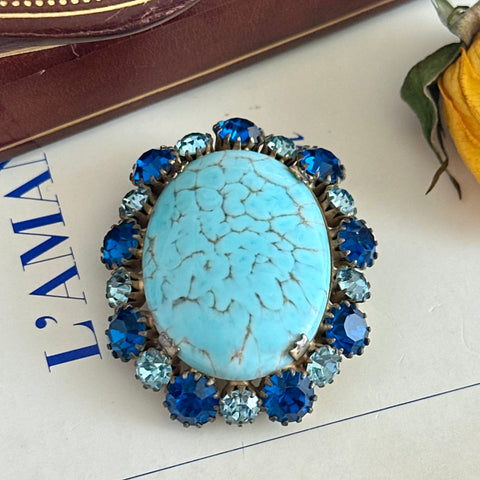 Vintage Czech statement brooch featuring a large faux turquoise Hubbell glass oval cabochon surrounded by alternating capri blue and light sapphire rhinestones in a gold‑tone prong‑set setting, shown from various angles.