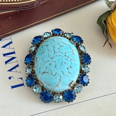Vintage Czech statement brooch featuring a large faux turquoise Hubbell glass oval cabochon surrounded by alternating capri blue and light sapphire rhinestones in a gold‑tone prong‑set setting, shown from various angles.