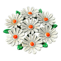 Vintage 1960s enamel daisy brooch with white petals, orange centers, and green leaves in a round floral cluster. Silver-toned finish, 2-inch diameter, in very good condition.