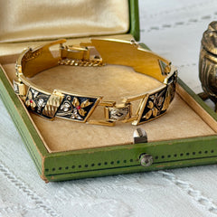 Vintage Spanish damascene gold‑tone bracelet with black enamel floral links, silver inlay, and red rhinestone accents, shown in various angles highlighting its 1960s Toledo craftsmanship and slide clasp with safety chain.