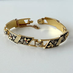 Vintage Spanish damascene gold‑tone bracelet with black enamel floral links, silver inlay, and red rhinestone accents, shown in various angles highlighting its 1960s Toledo craftsmanship and slide clasp with safety chain.