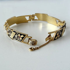 Vintage Spanish damascene gold‑tone bracelet with black enamel floral links, silver inlay, and red rhinestone accents, shown in various angles highlighting its 1960s Toledo craftsmanship and slide clasp with safety chain.