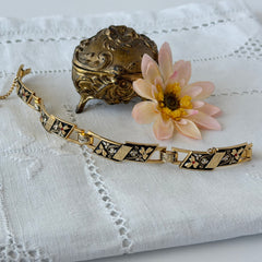 Vintage Spanish damascene gold‑tone bracelet with black enamel floral links, silver inlay, and red rhinestone accents, shown in various angles highlighting its 1960s Toledo craftsmanship and slide clasp with safety chain.