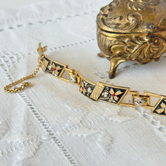Vintage Spanish damascene gold‑tone bracelet with black enamel floral links, silver inlay, and red rhinestone accents, shown in various angles highlighting its 1960s Toledo craftsmanship and slide clasp with safety chain.