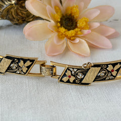 Vintage Spanish damascene gold‑tone bracelet with black enamel floral links, silver inlay, and red rhinestone accents, shown in various angles highlighting its 1960s Toledo craftsmanship and slide clasp with safety chain.