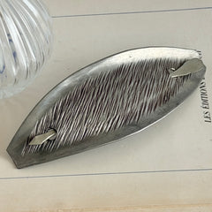 Vintage Danish S.I.D. pewter hair barrette with textured diagonal surface and signed back, elongated oval shape, 1970s–80s Scandinavian design.