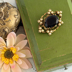Vintage gold‑tone Victorian Revival brooch with red faceted glass cabochon and faux pearls.