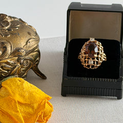 Vintage gold plated ring with an oval dark‑topaz CZ center stone and two clear rhinestone accents.
