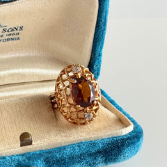 Vintage gold plated ring with an oval dark‑topaz CZ center stone and two clear rhinestone accents.