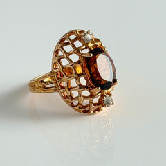 Vintage gold plated ring with an oval dark‑topaz CZ center stone and two clear rhinestone accents.