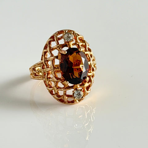 Vintage gold plated ring with an oval dark‑topaz CZ center stone and two clear rhinestone accents.