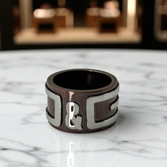 Dolce & Gabbana men's stainless steel ring with brown finish and raised silver-tone logo; bold designer accessory in size 8.5 with wide band styling.