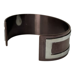 Dolce & Gabbana men's stainless steel cuff bracelet with a brown finish and raised silver-tone logo plaque; modern designer accessory with bold branding and sculptural detail.