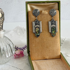Vintage Duri Art Deco‑style abalone and rhinestone dangle post earrings with ornate floral metalwork and iridescent inlay, shown on display and vintage box.