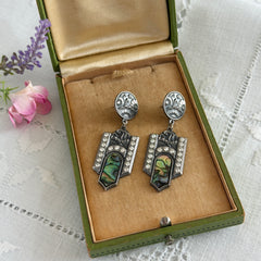 Vintage Duri Art Deco‑style abalone and rhinestone dangle post earrings with ornate floral metalwork and iridescent inlay, shown on display and vintage box.
