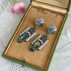 Vintage Duri Art Deco‑style abalone and rhinestone dangle post earrings with ornate floral metalwork and iridescent inlay, shown on display and vintage box.