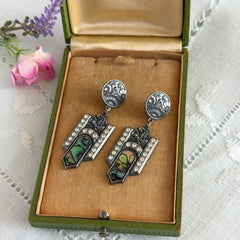 Vintage Duri Art Deco‑style abalone and rhinestone dangle post earrings with ornate floral metalwork and iridescent inlay, shown on display and vintage box.