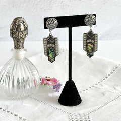 Vintage Duri Art Deco‑style abalone and rhinestone dangle post earrings with ornate floral metalwork and iridescent inlay, shown on display and vintage box.
